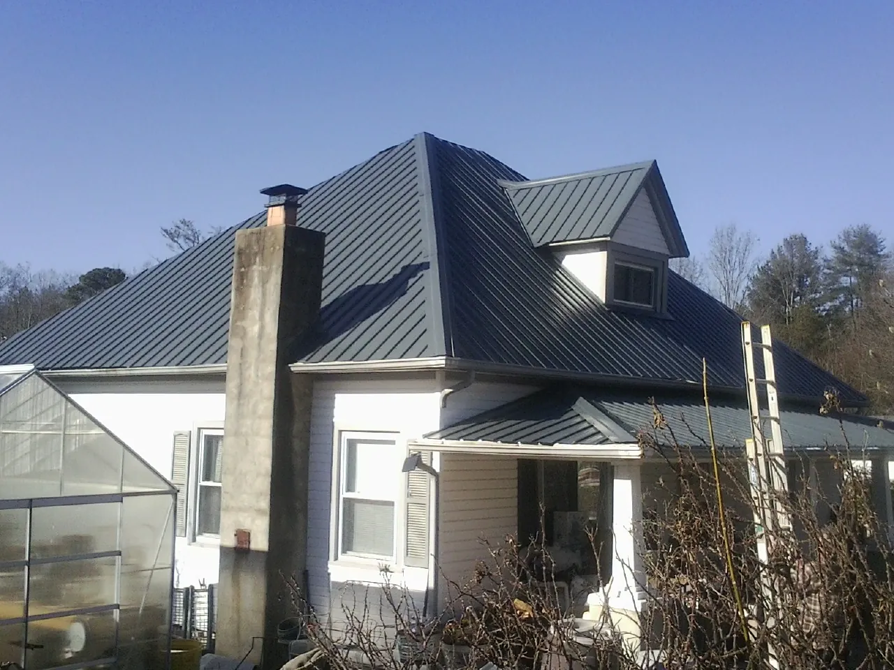 Dark blue standing seam metal roof on a white farmhouse with dormer — Slate & Tile Roof Repair by Roofing Brothers in Hayes