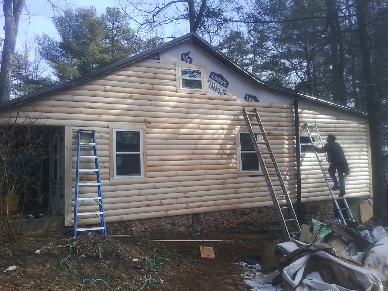 Ladders set against fresh log siding during an exterior remodel in Hayes