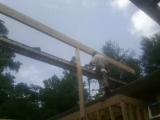 Carpenter setting a ridge beam over a new addition frame — Ice Dam Removal by Roofing Brothers in Hayes