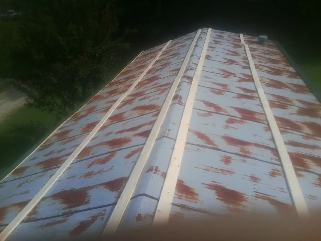 Rusted metal roof panels with new wood purlins before replacement — Storm Damage Roof Repair in Hayes by Roofing Brothers