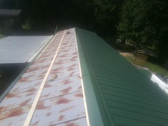 Old rusted panels beside newly installed green metal roofing — Wind Damage Roof Repair by Roofing Brothers in Hayes