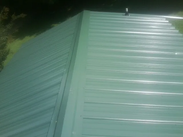 New green metal panels meeting at the ridge of a roof — Flat Roof Repair work by our crew in Hayes