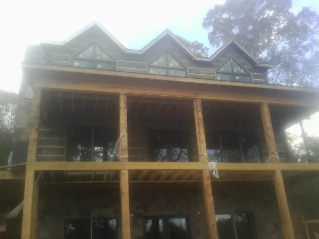Dormers and porch framing on a large log home under construction — Roof Coating work by our crew in Hayes