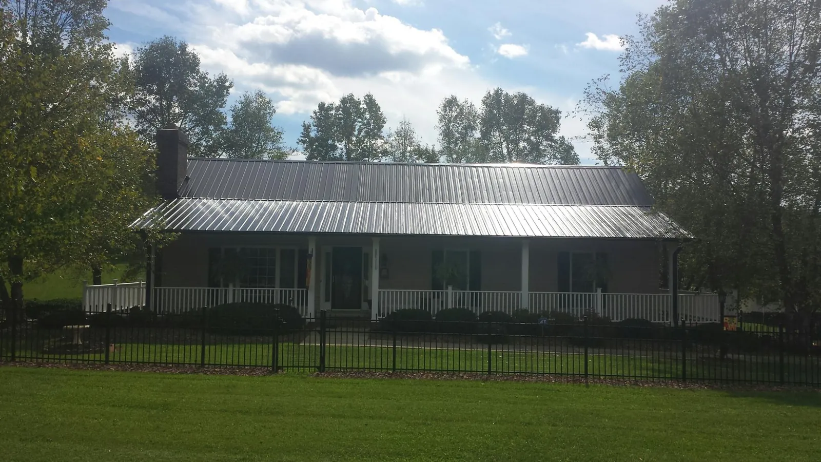 Gray metal roof on a brick ranch with a full width front porch — Gutter Guard Installation work by our crew in Hayes