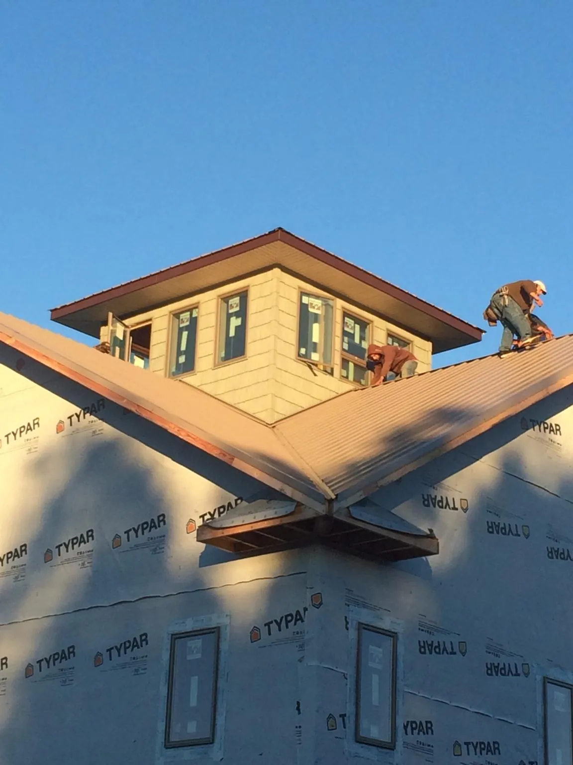 Roofers working around a rooftop cupola on a new metal roof at sunset — Roof Waterproofing in Hayes by Roofing Brothers